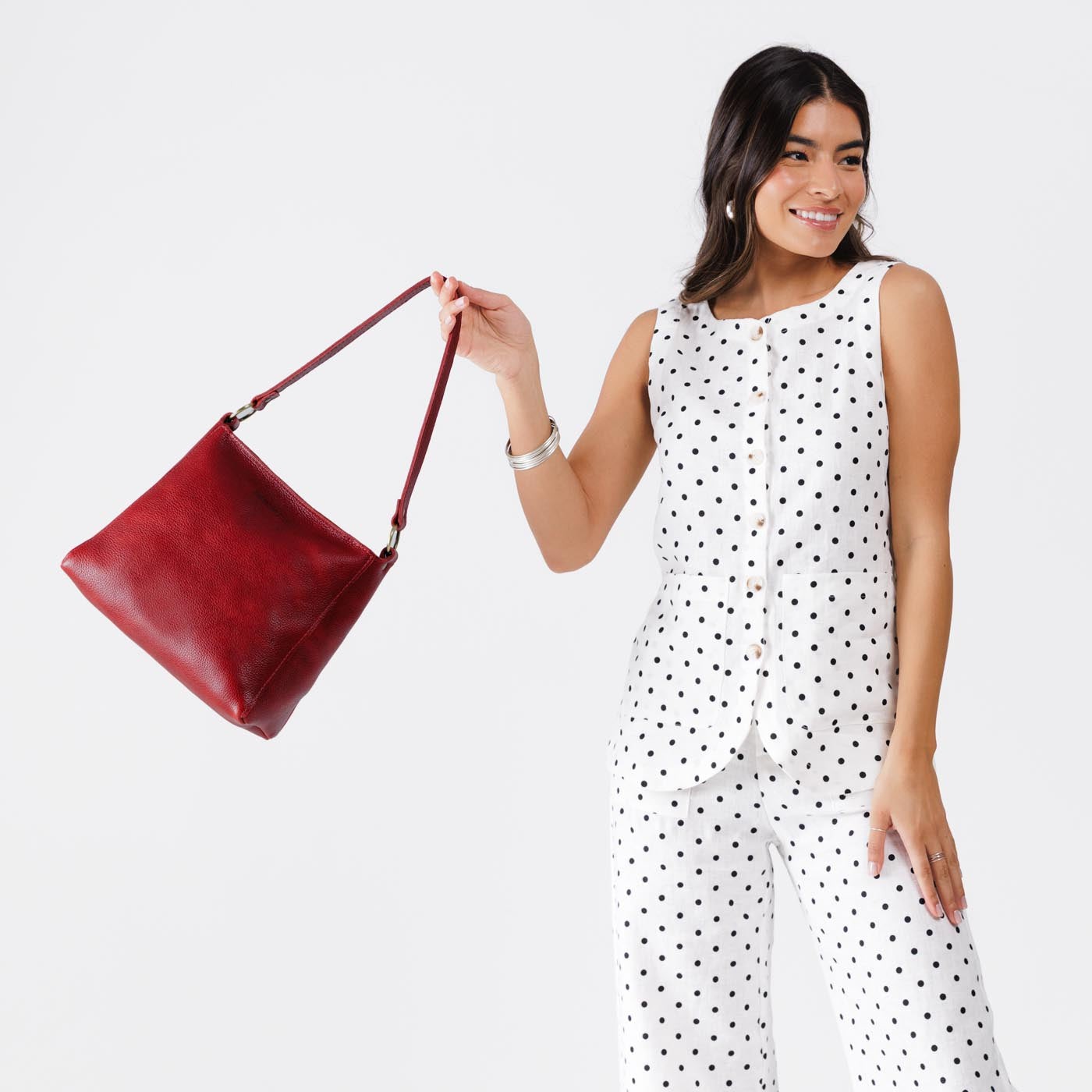 Chili Red*Classic | Model holding triangular shoulder bag with antiqued brass finished hardware
