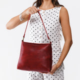Chili Red Classic | Model holding triangular shoulder bag with antiqued brass finished hardware