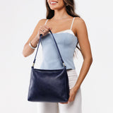 Cobalt Classic | Model holding triangular shoulder bag with antiqued brass finished hardware