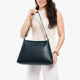 Boreal Large | Model holding large triangular shoulder bag with antiqued brass finished hardware