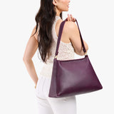Plum Large | Model carrying large triangular shoulder bag with antiqued brass finished hardware