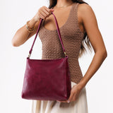 Orchid Classic | Model carrying leather triangular shoulder bag with zipper top closure and wide shoulder strap