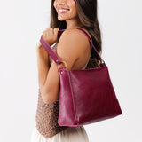 Orchid Classic | Model carrying leather triangular shoulder bag with zipper top closure and wide shoulder strap