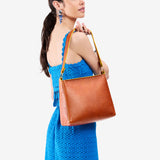 Sienna Classic | Model holding triangular shoulder bag with antiqued brass finished hardware