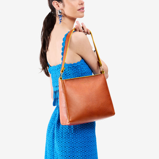 Sienna*Classic | Model holding triangular shoulder bag with antiqued brass finished hardware