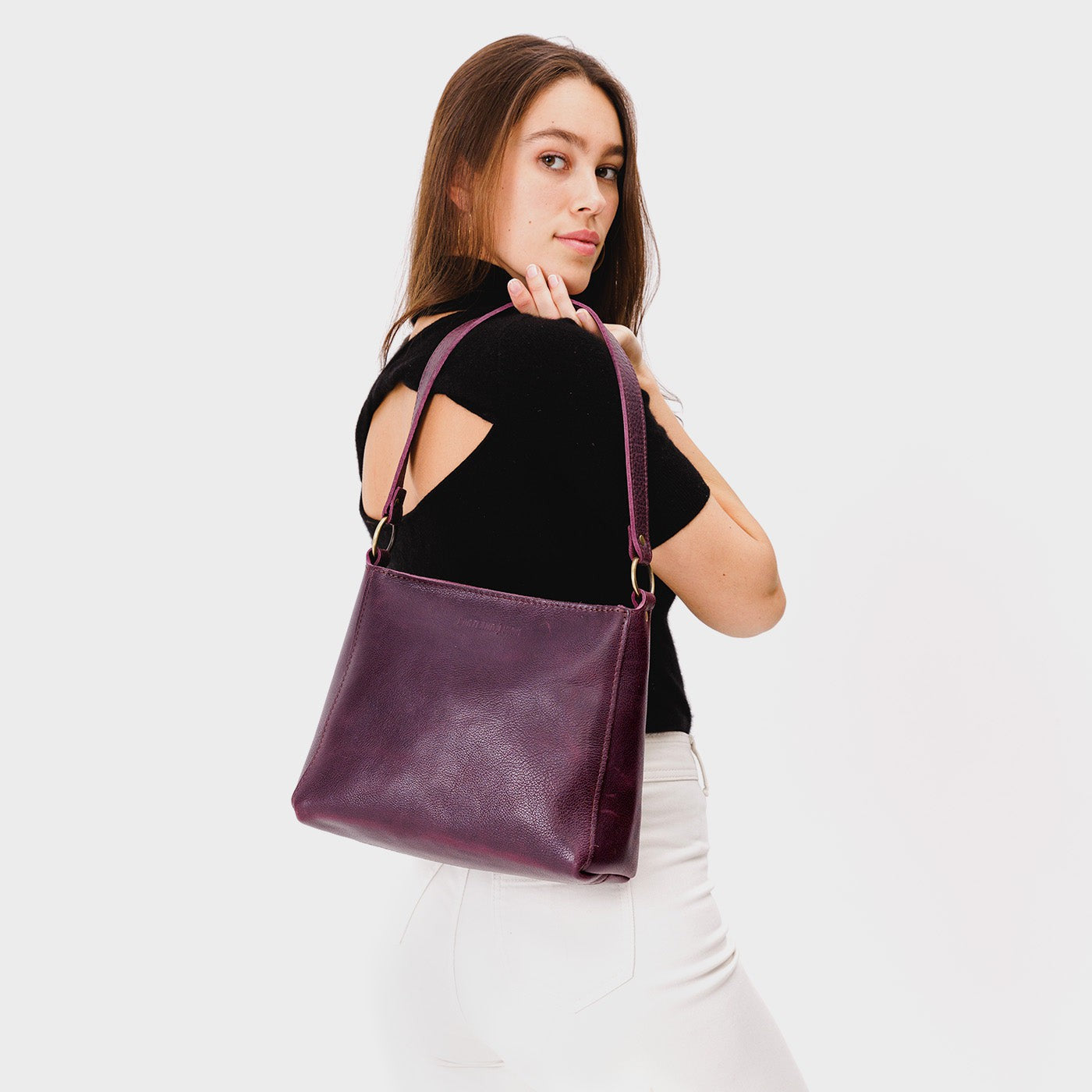 Plum*Classic | Model carrying triangular shoulder bag with antiqued brass finished hardware