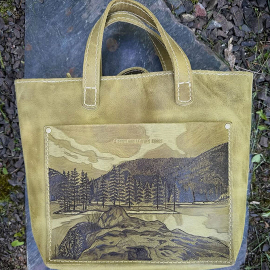 Green leather tote bag with a wild landscape engraving on the front pocket