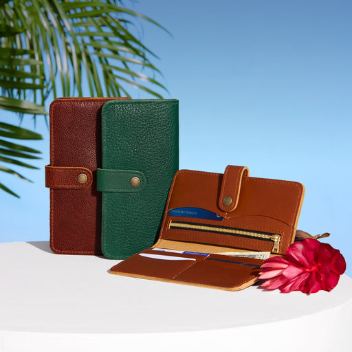 Three leather wallets in brown, green, and open brown wallet with a flower on a white surface with blue sky and palm leaves. featured image