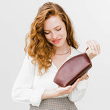 All Color: Cognac | Spacious leather makeup bag with curved seams and top zipper