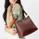 Cognac Classic | Model carrying triangular shoulder bag with antiqued brass finished hardware